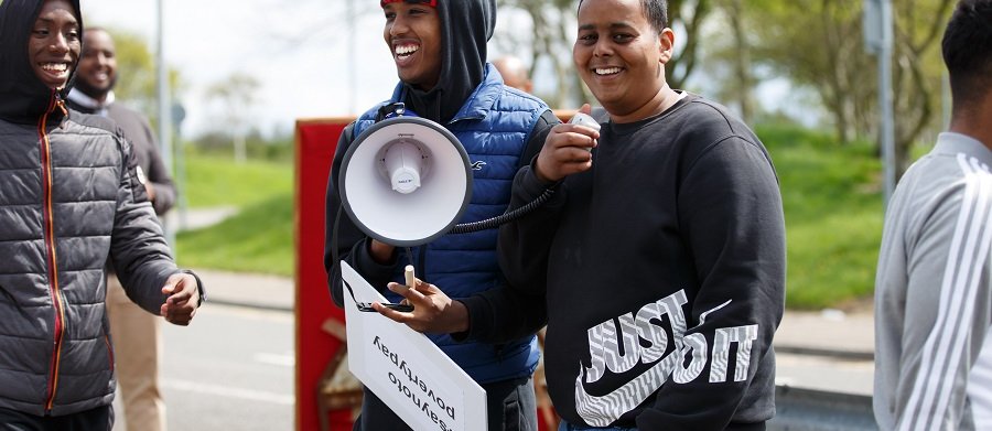 Three men laughing with two men holding a megaphone and poster