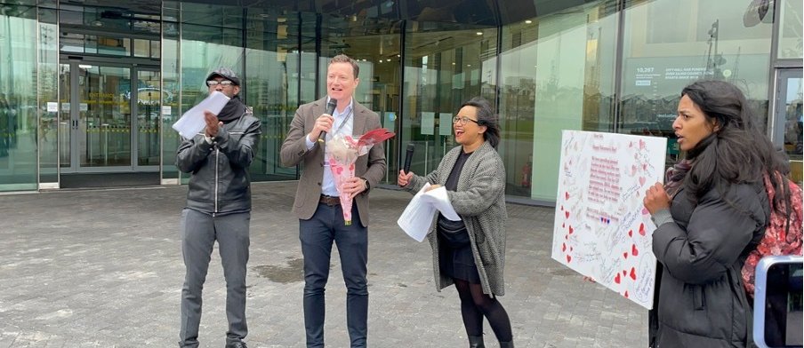 Deputy Mayor of London, Seb Dance, stands outside London City Hall alongside community organisers as he receives valentines day flowers and a card
