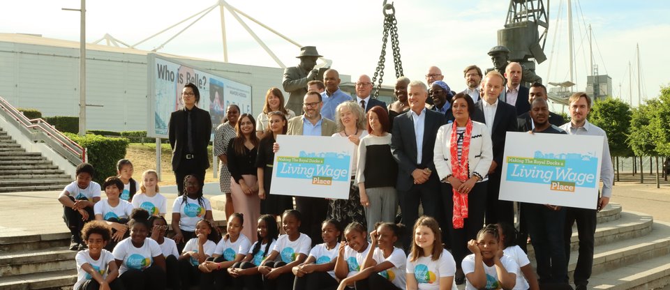 Group of St Antony's school kids in Living Wage Foundation t-shirts and business leaders from across Royal Docks with Rokhsana Fiaz outside the ExCel Centre holding Living Wage Places signs