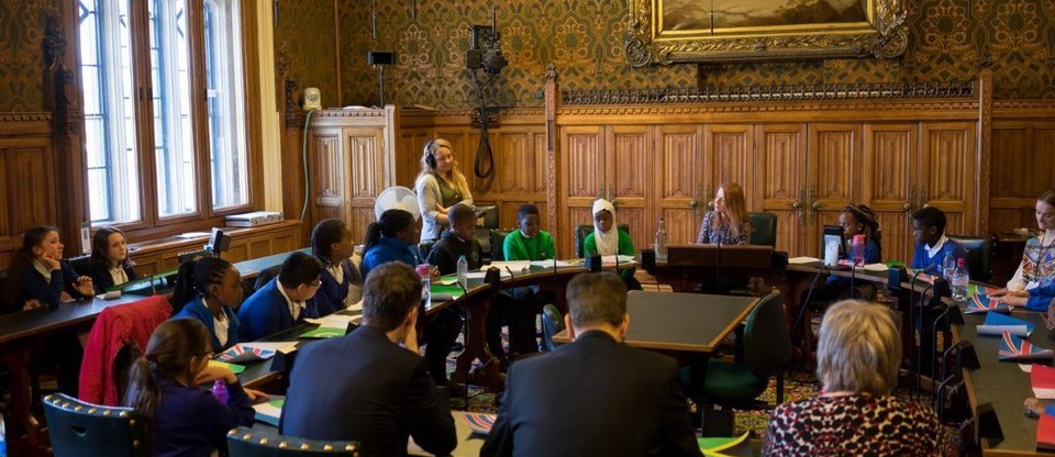 Pupils and community leaders sit at a round table in Parliament discussing the Children into Citizens campaign
