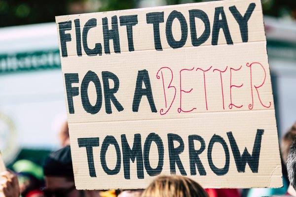 Banner held by a person at a protest saying 'Fight today for a better tomorrow'.