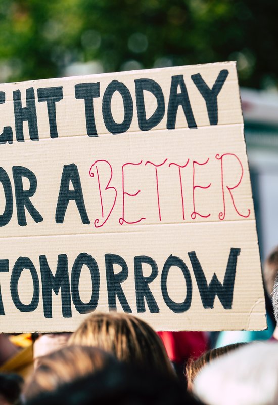 Banner held by a person at a protest saying 'Fight today for a better tomorrow'.