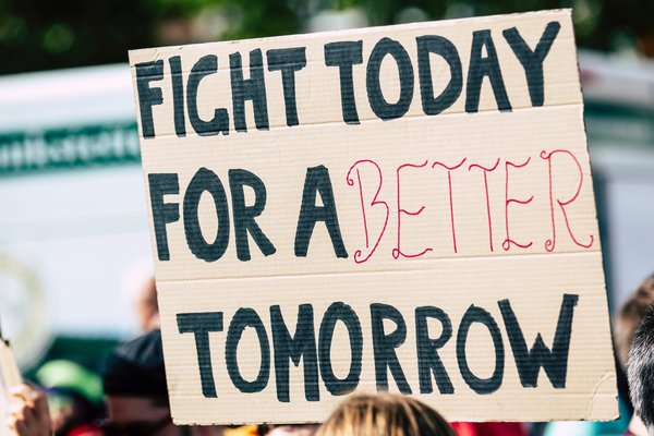 Banner held by a person at a protest saying 'Fight today for a better tomorrow'.
