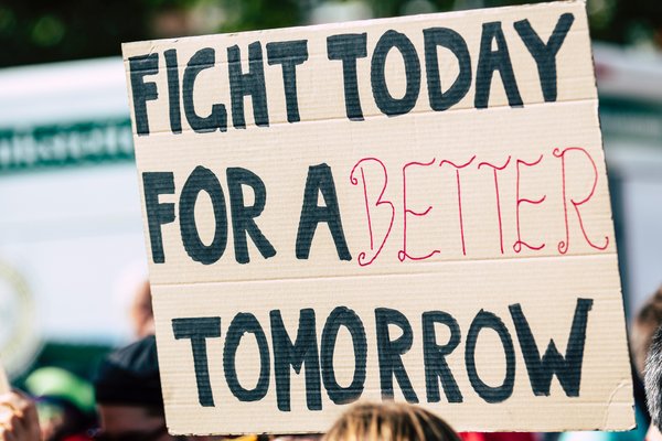 Banner held by a person at a protest saying 'Fight today for a better tomorrow'.
